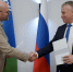 Ректор ЮГУ Роман Кучин и руководитель академического направления Фонда региональных социальных программ «Наше будущее» Пётр Сафронов поживают руки на фоне флагов России, Югры и ЮГУ в знак подписания соглашения - ЮГУ