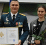 На фотографии изображены два человека: мужчина в военной форме и девушка в сером пиджаке. Мужчина стоит слева, он держит в руках рамку с текстом, в которой можно различить слова - ЮГУ
